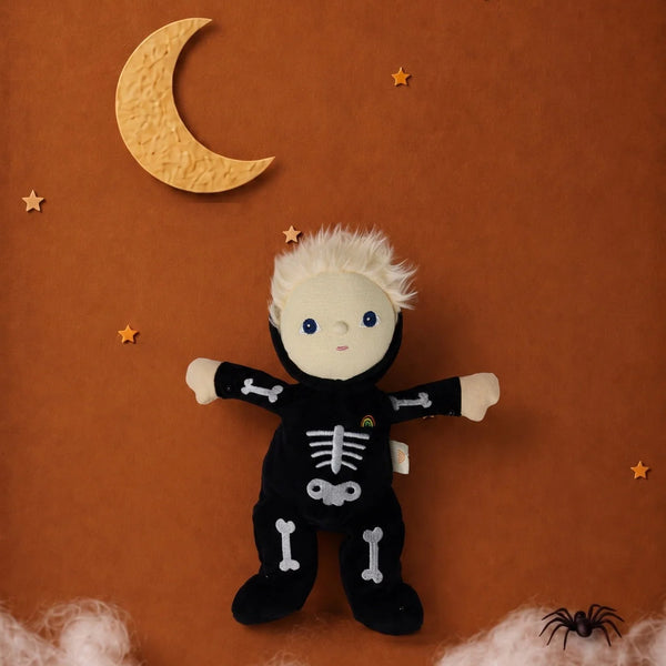 An Olli Ella Dinky Dinkum Doll - Scully Skeleton dressed in a black costume, positioned against an orange background with decorative stars, a crescent moon, and a small spider.