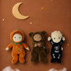 Three dolls, including an Olli Ella Dinky Dinkum Doll - Wesley Werewolf dressed as a werewolf, alongside two others in pumpkin and skeleton costumes, positioned beneath a crescent moon and stars on a brown background.