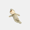 The Olli Ella Dozy Dinkum - Pickle is a soft cotton doll in a light green hooded onesie with a rainbow patch, lying on its side with closed eyes and a peaceful expression—an ideal first toy for babies.