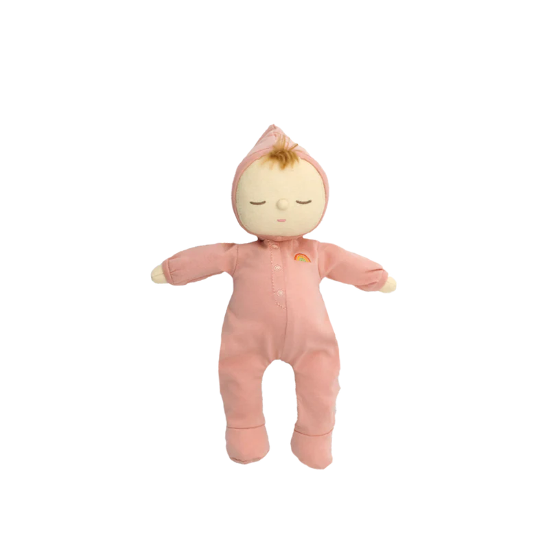 The Olli Ella Dozy Dinkum - Moppet is a soft cotton baby doll in a pink hooded onesie with a rainbow detail, closed eyes, and a light brown tuft of hair peeking out—adorably set against a plain white background.