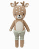 Cuddle + Kind Elliott the Fawn is a sustainable, fair trade, hand-knit plush doll featuring antlers, a light brown body with white spots, and light green drawstring pants, shown upright against a white background.