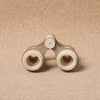A pair of Wooden Binoculars For Pretend Play placed on a textured beige background, viewed from the front showing the circular lens openings.