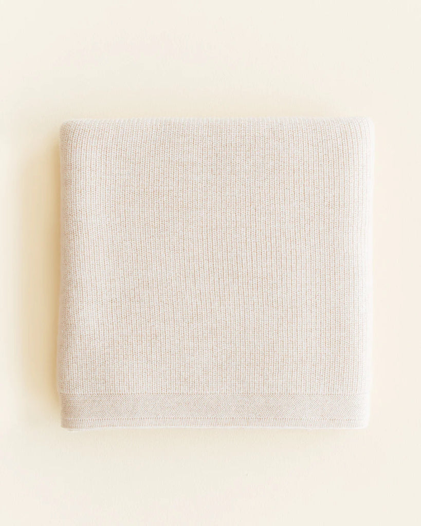 A neatly folded Handmade Merino Wool Felix Blanket in Cream on a plain, off-white background, emphasizing simplicity and cleanliness for sensitive skin.