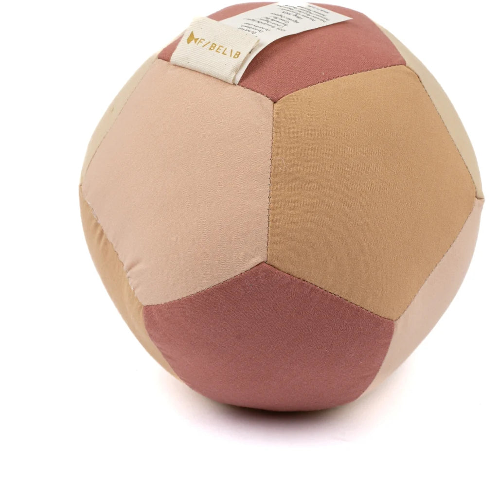 The Fabric Ball - Dusty Rose is a soft organic cotton baby ball with stitched beige, pink, and light brown panels and a small fabric tag—perfect as a gentle developmental toy for little ones.