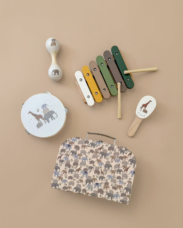 Aerial view of the Konges Sløjd - Music Set - Safari on a beige background, featuring a white maraca, colorful xylophone, tambourine with animal illustrations, a small drumstick, and suitcase instruments adorned with an animal pattern.