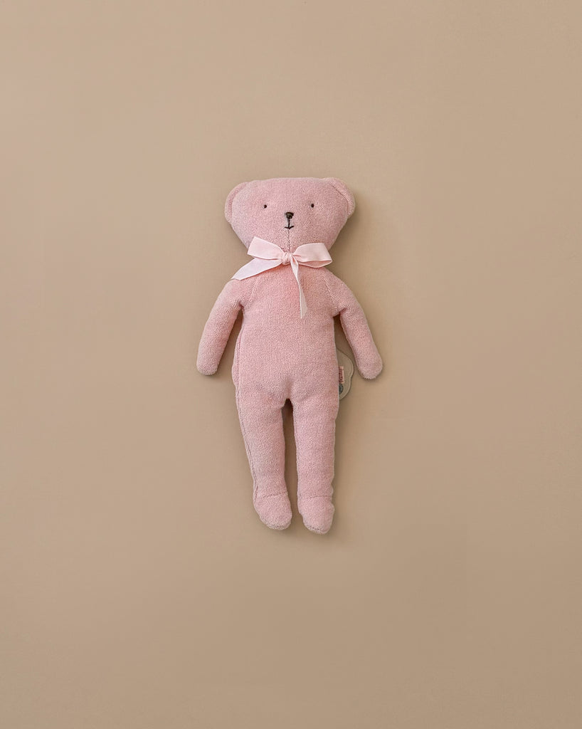 The Maileg Teddy - Rose, a cuddly pink teddy bear with soft fabric and a bow around its neck, is positioned upright against a plain beige background.