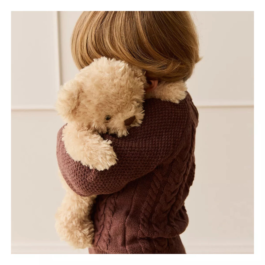 A young child in a textured brown sweater cuddles Snuggle Bunnies - Arthur the Bear, their faces nestled together in its ultra-soft plush.