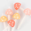 A collection of Meri Meri Mushroom Birthday Candles with tops shaped like colorful mushrooms, featuring red and yellow caps speckled with white dots, set against a soft white background.