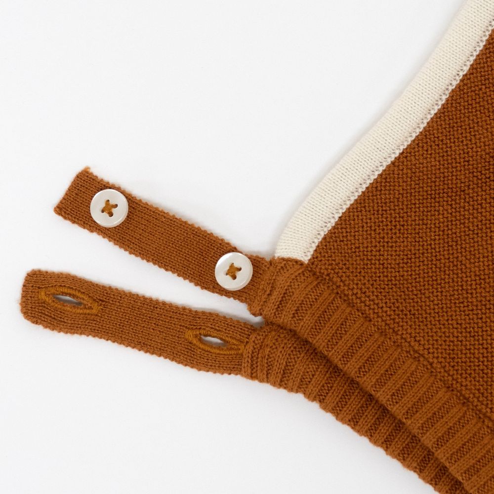 Close-up of a Meri Meri Fox Bonnet & Booties Set with detailed stitching and two wooden buttons on adjustable straps against a white background, perfect as a baby shower gift.