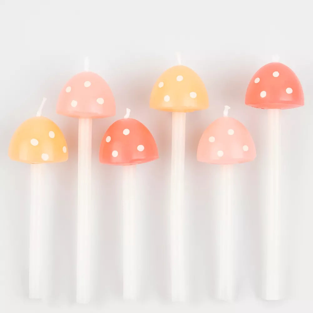 Seven Meri Meri Mushroom Birthday Candles shaped like mushrooms with white stems and colorful caps in pastel shades, arranged in a row against a white background.