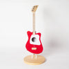A red Loog Mini guitar with a white center, mounted upright on a circular wooden Guitar Stand For Loog Mini against a plain white background.