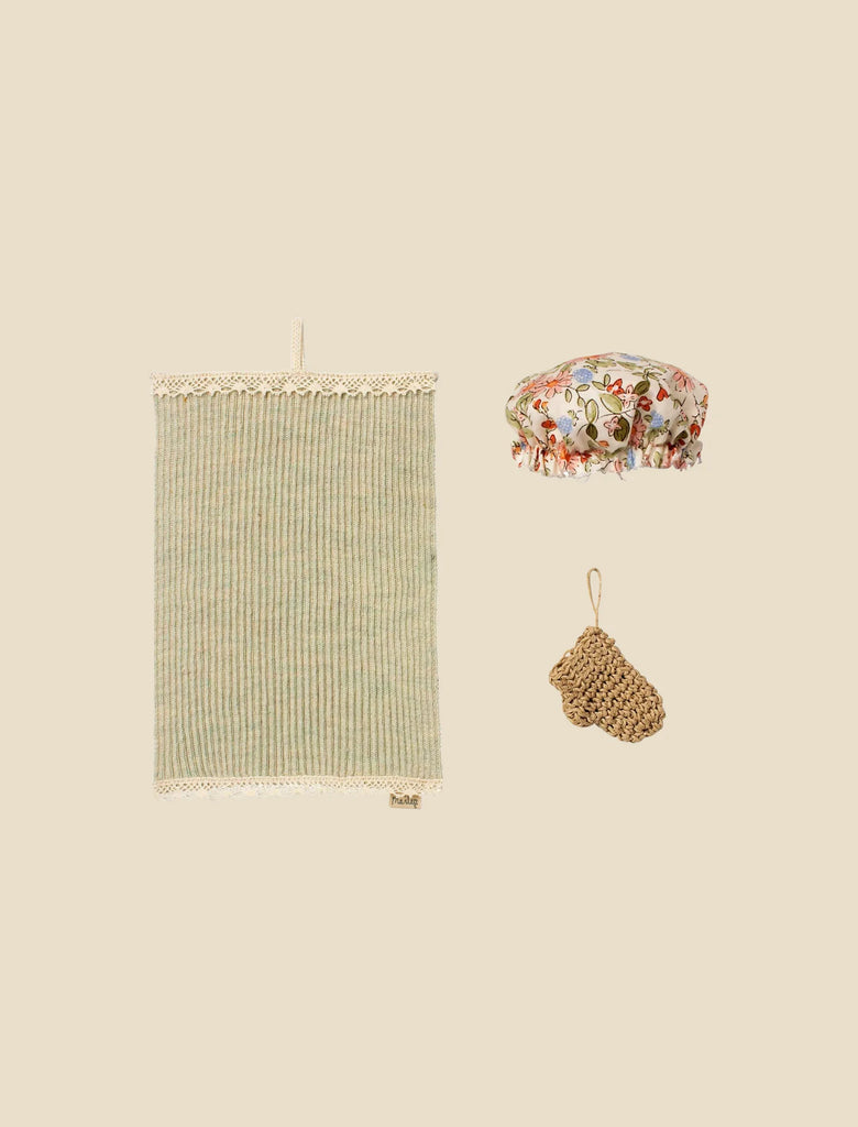 The Maileg Bathroom Set, featuring a green and beige striped towel, a floral shower cap, and a brown woven soap pouch, is neatly arranged on a plain beige background.