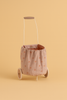 The Maileg Trolley, Multi dots - Rose is a small, washable cart with a metal handle and beige linen body covered in pink polka dots, displayed against a solid peach backdrop.