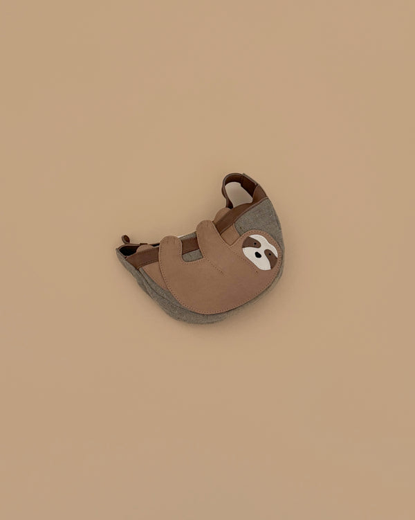 The Donsje Leather Talei Bumbag Purse - Sloth is a small, brown and gray kids bag shaped like a smiling sloth, featuring an adjustable strap, shown on a plain beige background.
