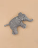 The Senger Naturwelt Cuddly Animal - Elephant is a soft, gray plush toy made from organic cotton with floppy ears, a long trunk, and small black eyes, lying on a plain light brown background. It doubles as a comforting warming pillow.