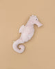 The Senger Naturwelt Cuddly Animal - Seahorse is a soft, light pink plush with a curled tail and stitched eye, resting on a beige background—GOTS-certified and perfect for little ones.