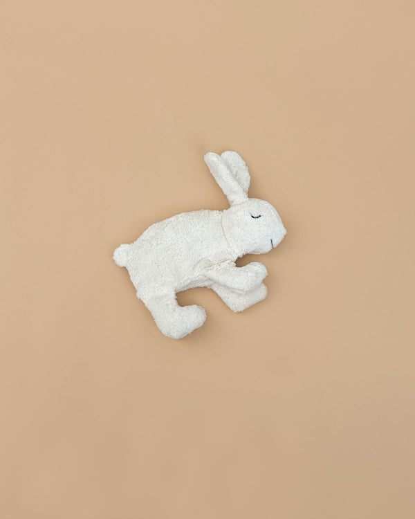 A Senger Naturwelt Cuddly Animal - White Bunny with closed eyes rests on a plain beige background, ideal for snuggling or as a gentle heat pack.