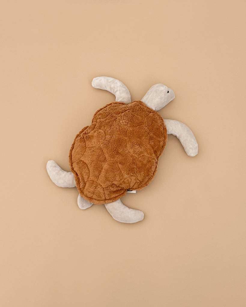 A Senger Naturwelt Cuddly Animal - Turtle with a brown, textured shell and white flippers and head is shown lying on a plain beige background.
