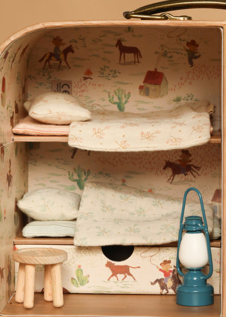 The Maileg Fully Furnished SuitCasa Set is a miniature mouse house room with cowboy-themed wallpaper, two bunks with bedding, a wooden stool, and a blue lantern on the floor.