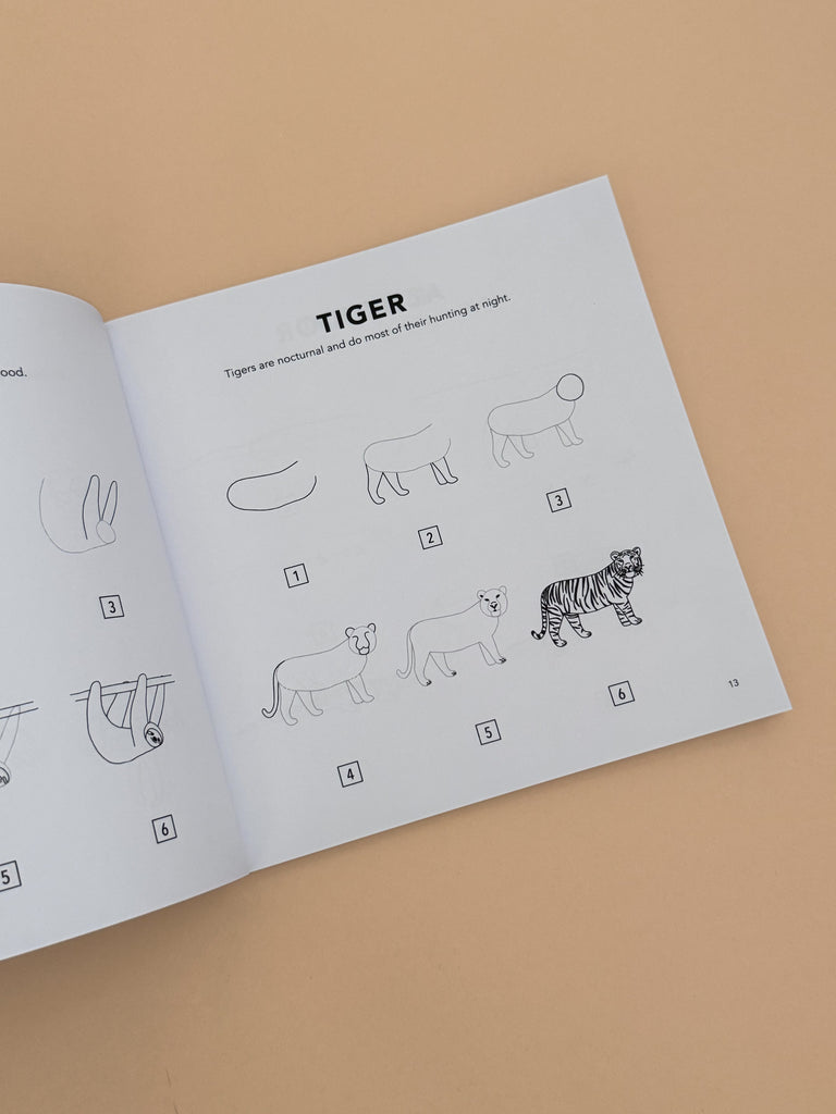 An open copy of "All the Animals: How To Draw Books For Kids" displays step-by-step tiger drawing instructions on a plain light tan background. Ideal for children learning to draw animals.