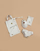 The Konges Sloejd Doll Nursery Set - Lemon features white organic cotton doll accessories with small yellow lemon prints: a bib, a bag, bloomers, and a folded cloth, all shown on a beige background.