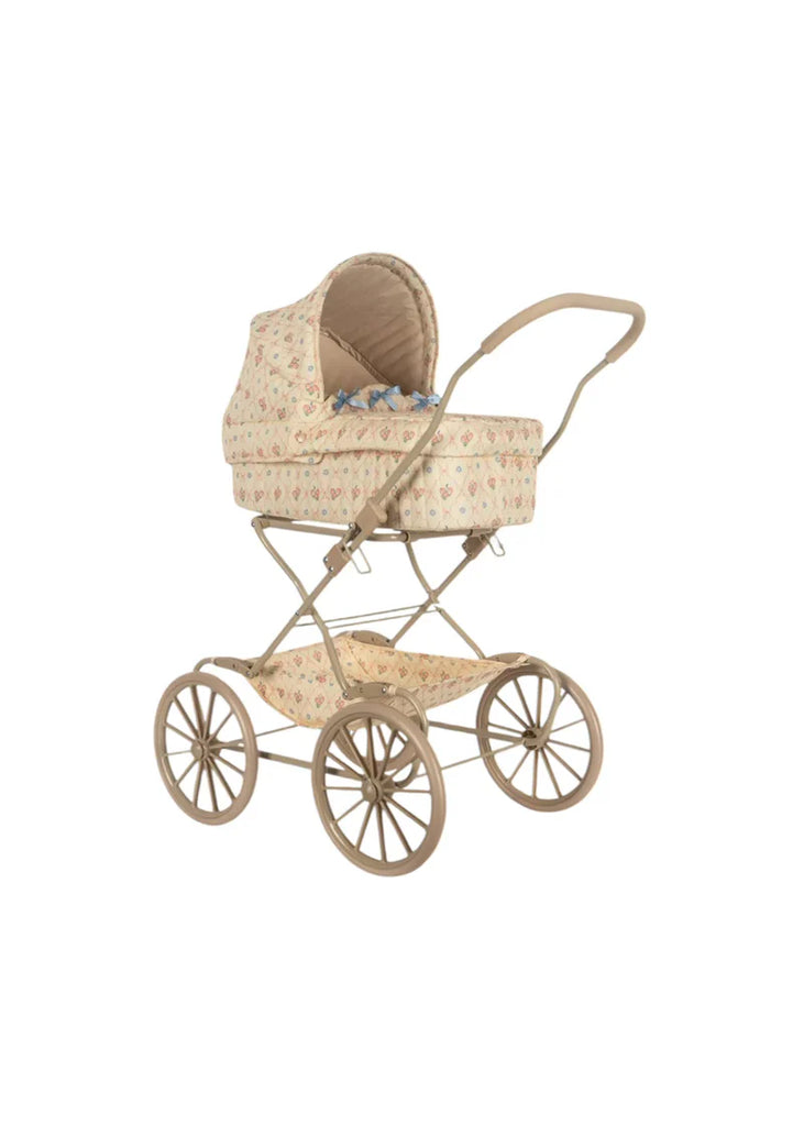 The Doll Pram - Fleur Decor, with its vintage charm reminiscent of a classic baby carriage, features a beige floral-patterned fabric. It is equipped with large spoked wheels and a curved handle, providing ample space that includes an organic cotton mattress. The partially raised hood offers a glimpse of the blue blanket inside. This product ships in approximately two weeks.