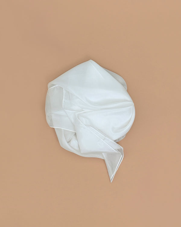 Sarah's Silks Solid Color Playsilk - White: a semi-transparent, 100% pure silk fabric, loosely folded on a plain light brown background. Ideal for open-ended play.