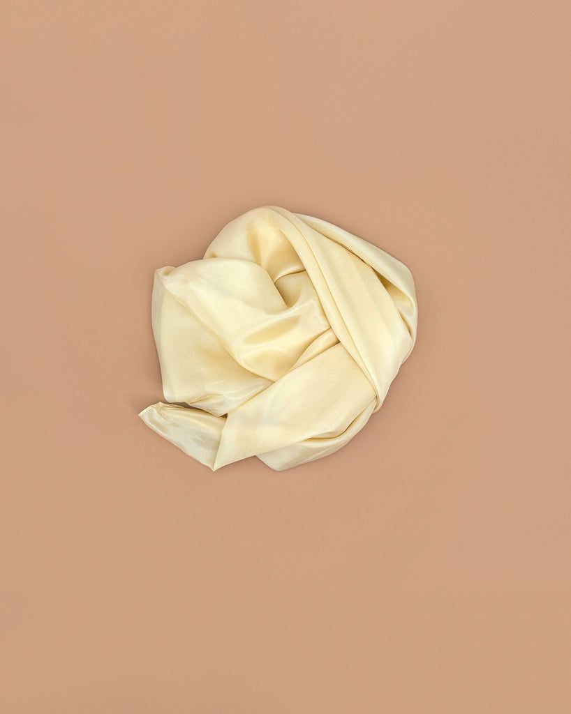 Sarah's Silks Giant Playsilk - Lambswool is a crumpled, light cream-colored mulberry silk scarf resting on a solid beige background—ideal for Waldorf-inspired play or as a versatile accessory.