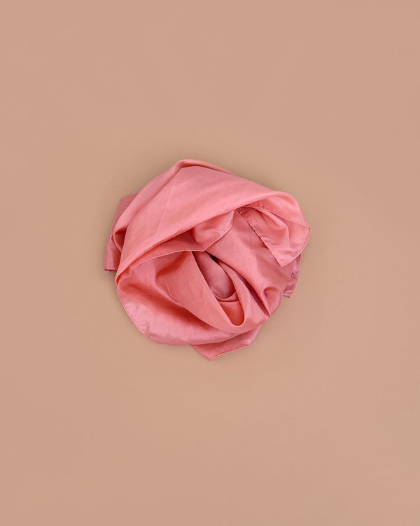 Sarah's Silks Solid Color Playsilk in Peach, perfect for sensory play, is softly crumpled and arranged in a loose circle on a light brown background.