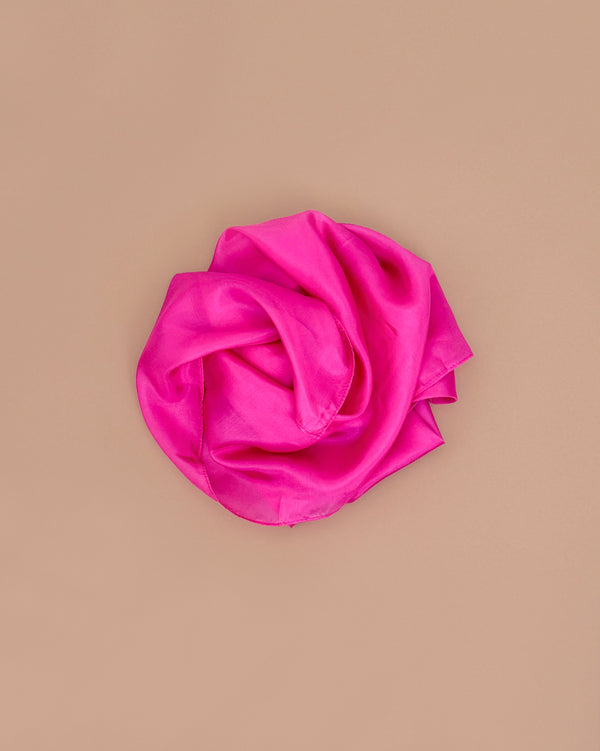 Sarah's Silks Solid Color Playsilk - Rose is neatly rolled in a circle on a plain beige background, inviting open-ended play and sensory exploration.