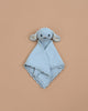 The Cuddle + Kind Organic Cotton Baby Bunny Lovey in baby blue is a soft, heirloom-quality security blanket with a plush bunny head and ears at the center, shown on a plain beige background.