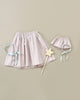 A Minikane | Little Fairy Costume In Petal Pink For Child and Doll is displayed on a beige background. The set includes an elastic-waist skirt, a matching smaller skirt, a headband with blue ribbons, and a wooden magic wand.
