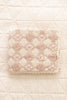 The Organic Cotton Baby Patchwork Blanket - Pink Bows (ships in one week), featuring a diamond quilted pattern and lace trim, is folded on a textured, cream-colored surface.