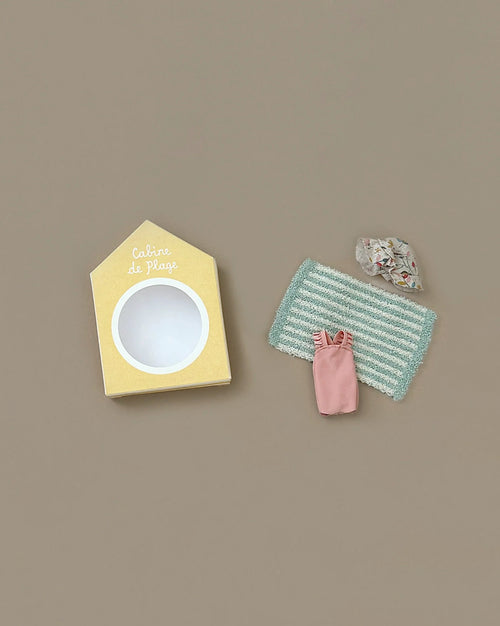 The Maileg Beach Bundle for Big Sister includes a yellow house-shaped box labeled "Cabine de Plage," a striped mat, a pink dress, and patterned beach accessories for mice, perfect for beach fun with your big sister mouse.