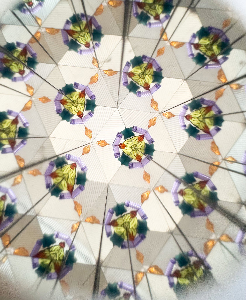 The Konges Sloejd Kaleidoscope - Tiger features a lively, symmetrical abstract design with repeating geometric shapes in yellow, green, purple, and orange for a vibrant kaleidoscope effect.