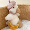 Mon Ami - Colette the Duck Plush Toy features a soft French duckling with a pink acorn hat, floral scarf, and yellow bread, nestled in a woven basket on a star-patterned blanket—an adorable snuggle gift for any occasion.