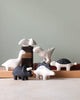 A collection of handcrafted wooden animal figurines including birds, a Handmade Tiny Wooden Dinosaurs - Brachiosaurus, and various mammals on a table, against a soft green background.