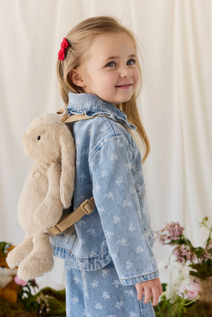 A young girl wearing a denim jacket and a hazelnut Snuggle Bunnies - Penelope Backpack - Hazelnut.