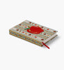 The Schoolhouse Mini Embroidered Journal is a closed hardbound notebook with a decorative cover featuring colorful, embroidered-like patterns and a large red apple design, plus a red ribbon bookmark.