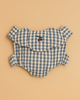 The Konges Sloejd Doll Carrier in Blue Checkers, shown beside a blue and white gingham baby romper with ruffled sleeves and cherry embroidery, makes a charming cotton accessory for your child's doll.
