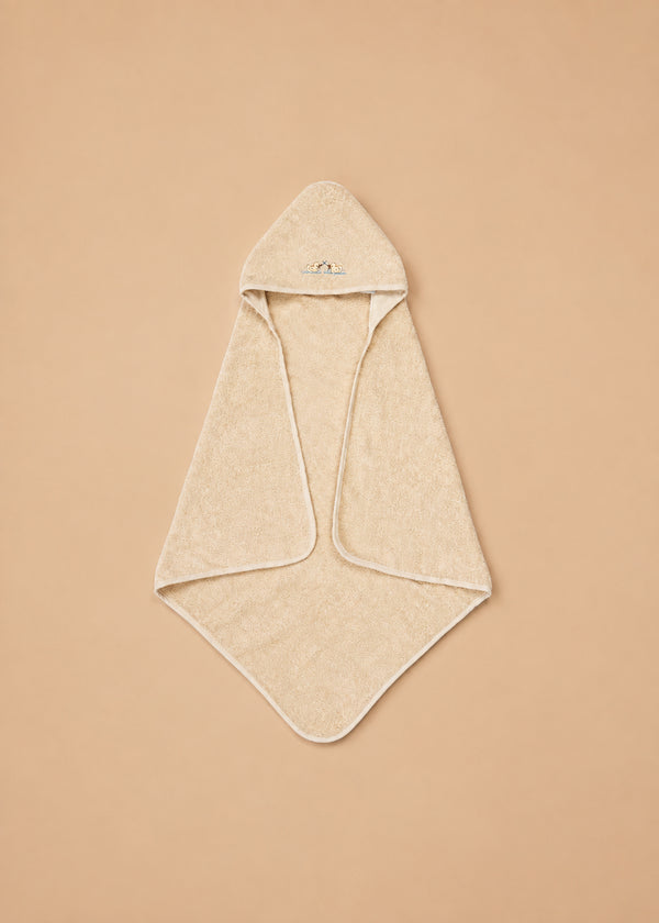 The Konges Sloejd Organic Cotton Baby Towel, in a beige shade with a hood and rounded corners, is displayed flat on a tan background. The soft towel features a small embroidered design on the hood.