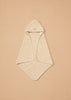 The Konges Sloejd Organic Cotton Baby Towel, in a beige shade with a hood and rounded corners, is displayed flat on a tan background. The soft towel features a small embroidered design on the hood.