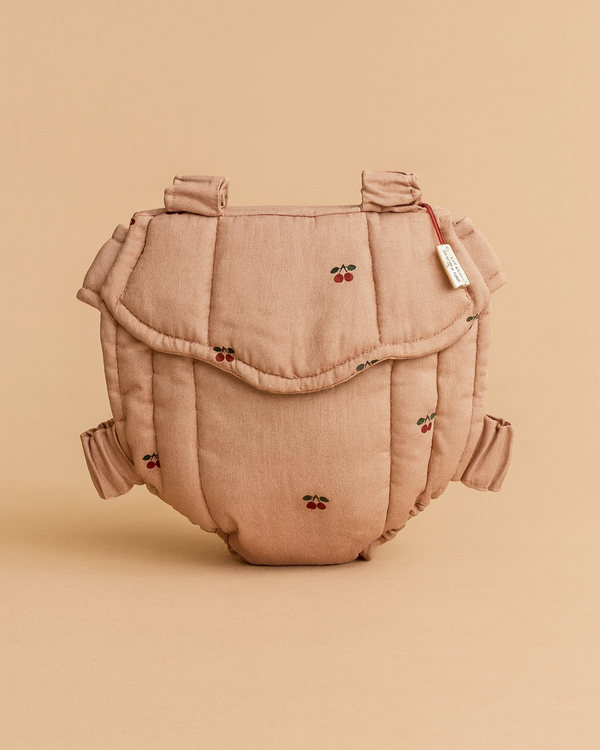 The Konges Sloejd Doll Carrier - Cherry Blush is a soft, padded cotton carrier in light brown with embroidered red cherries, shown upright against a matching beige background.