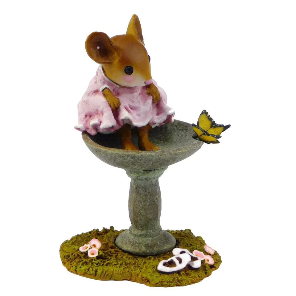 The Wee Forest Folk Tiny Collectible - Garden Spa features a hand-sculpted mouse in a pink dress by a birdbath, gazing at a yellow butterfly, with tiny pink shoes on the grass for added charm.
