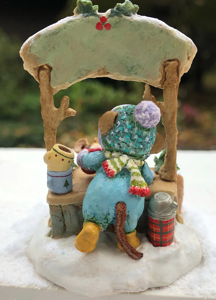 Wee Forest Folk Tiny Collectible - Hot Cocoa Comin' Up! features a hand-sculpted mouse in a blue coat, striped scarf, and yellow boots at a snowy stall with a mug, thermos, plaid container, and green awning with red berries.