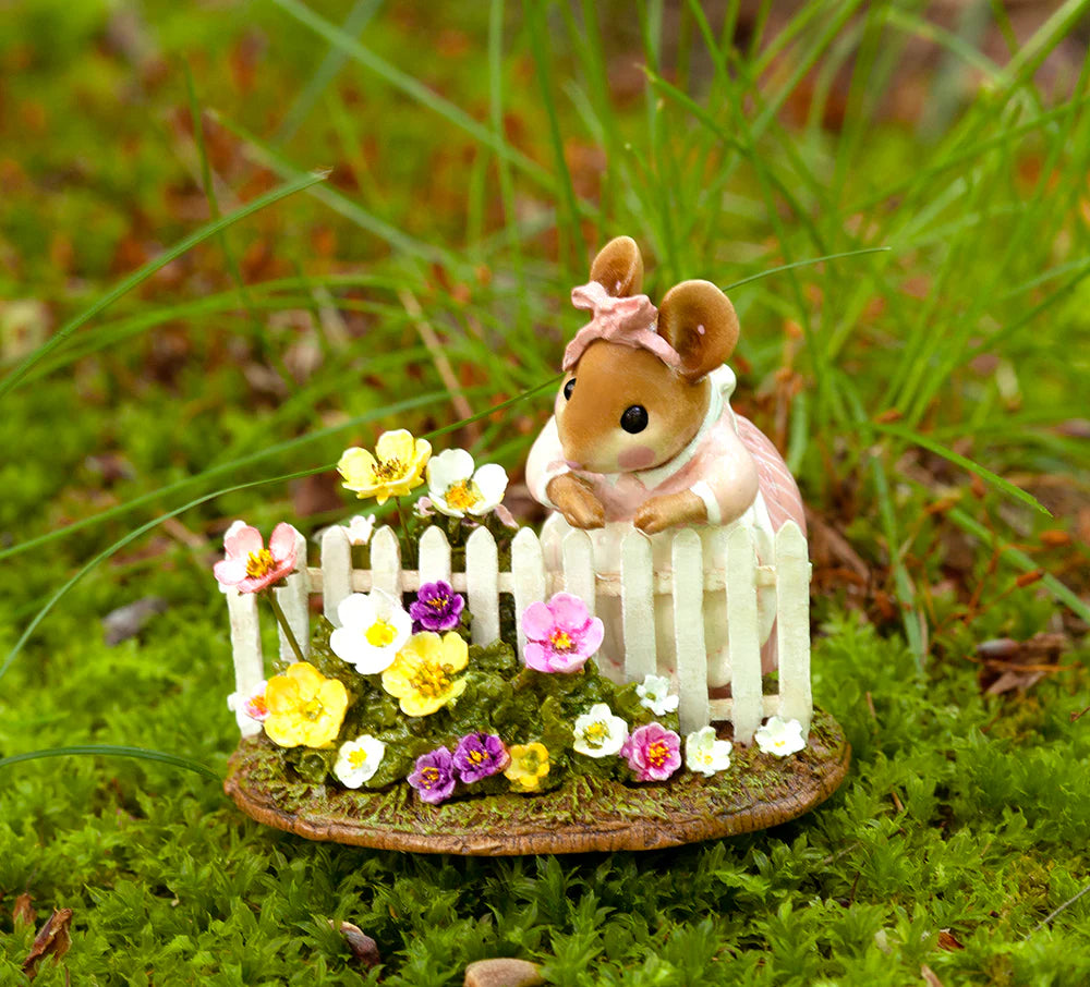 The Wee Forest Folk Tiny Collectible - Annette's Garden features a mouse in a pink dress and bow behind a white picket fence, surrounded by colorful flowers on a mossy green base.