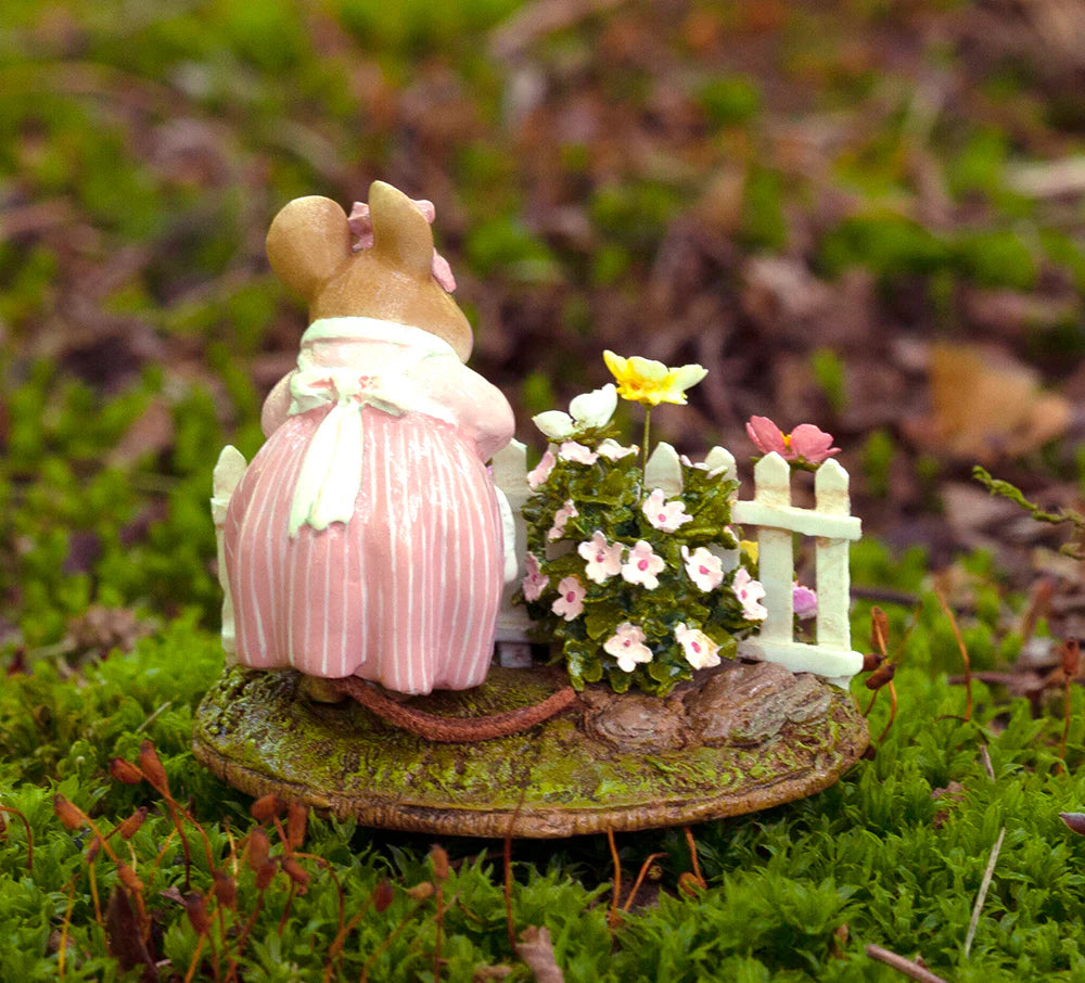 Annette’s Garden by Wee Forest Folk is a hand-sculpted collectible miniature mouse in a pink dress and white apron, standing by a white picket fence with flowers on mossy ground—a delightful piece for collectors.