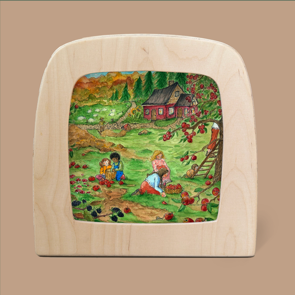 An artwork titled "Silhouette Only - Red Cottage: Autumn for Toverlux Lamp" features a vivid wooden-framed depiction of an idyllic countryside scene with people picking apples near a tree beside a red cottage, utilizing a ladder against the tree. The backdrop showcases green fields and mountains beneath an autumn silhouette sky.