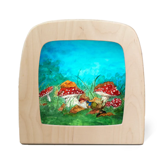 The Silhouette Only - Snoozy for Toverlux Lamp features whimsical red and white mushrooms clustered in a green forest under a bright blue sky, enhanced by grass and leaves, creating an enchanting scene.