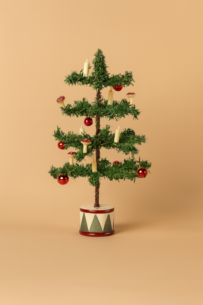 The Maileg Santa Mouse Christmas Set features a small artificial Christmas tree with red baubles, white candles, and a geometric-patterned round base, ready to welcome the festive Maileg Santa Mouse, against a plain beige background.